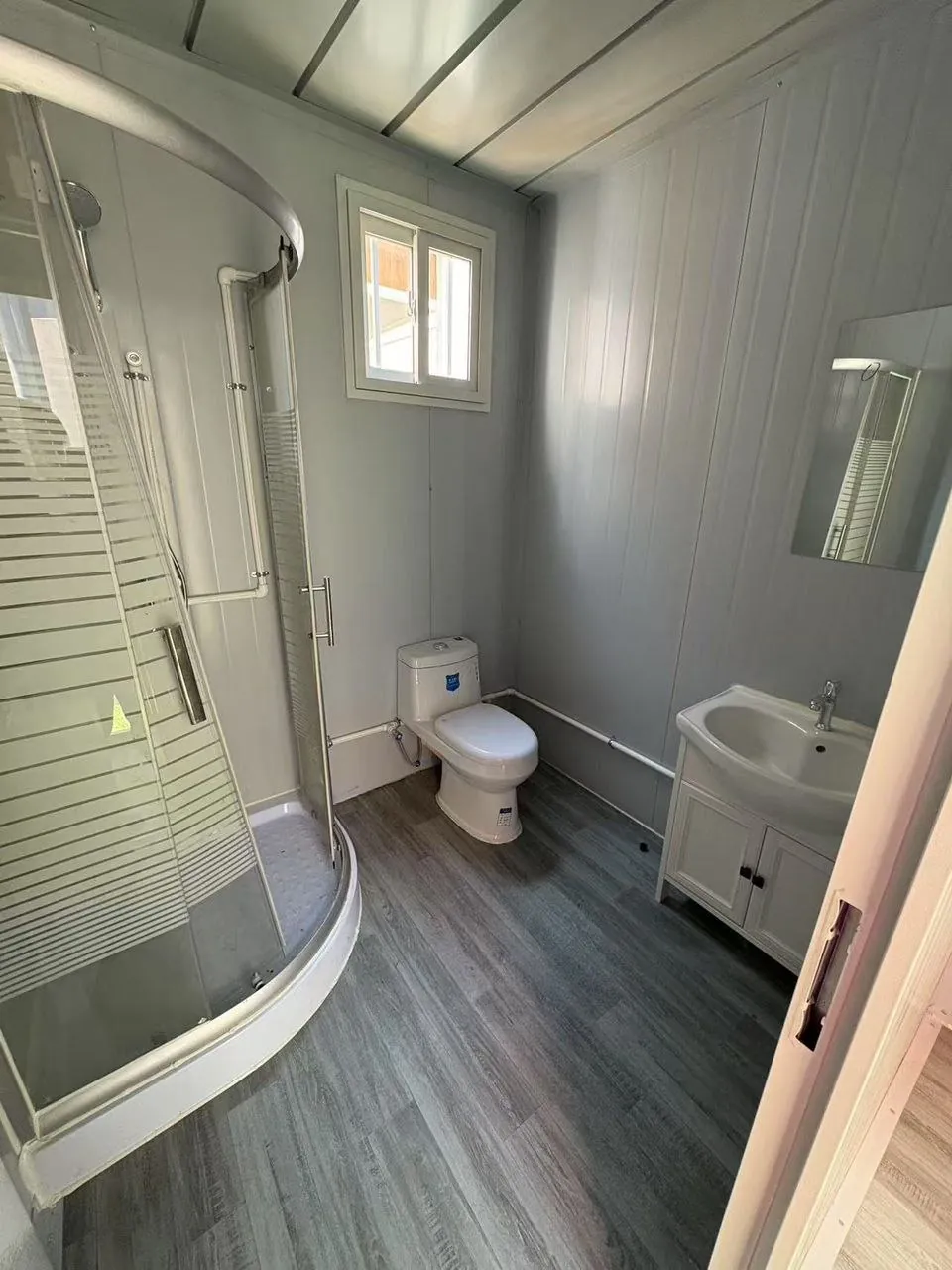 Baño con separación entre zona seca y húmeda, mampara curva y mueble vanitorio